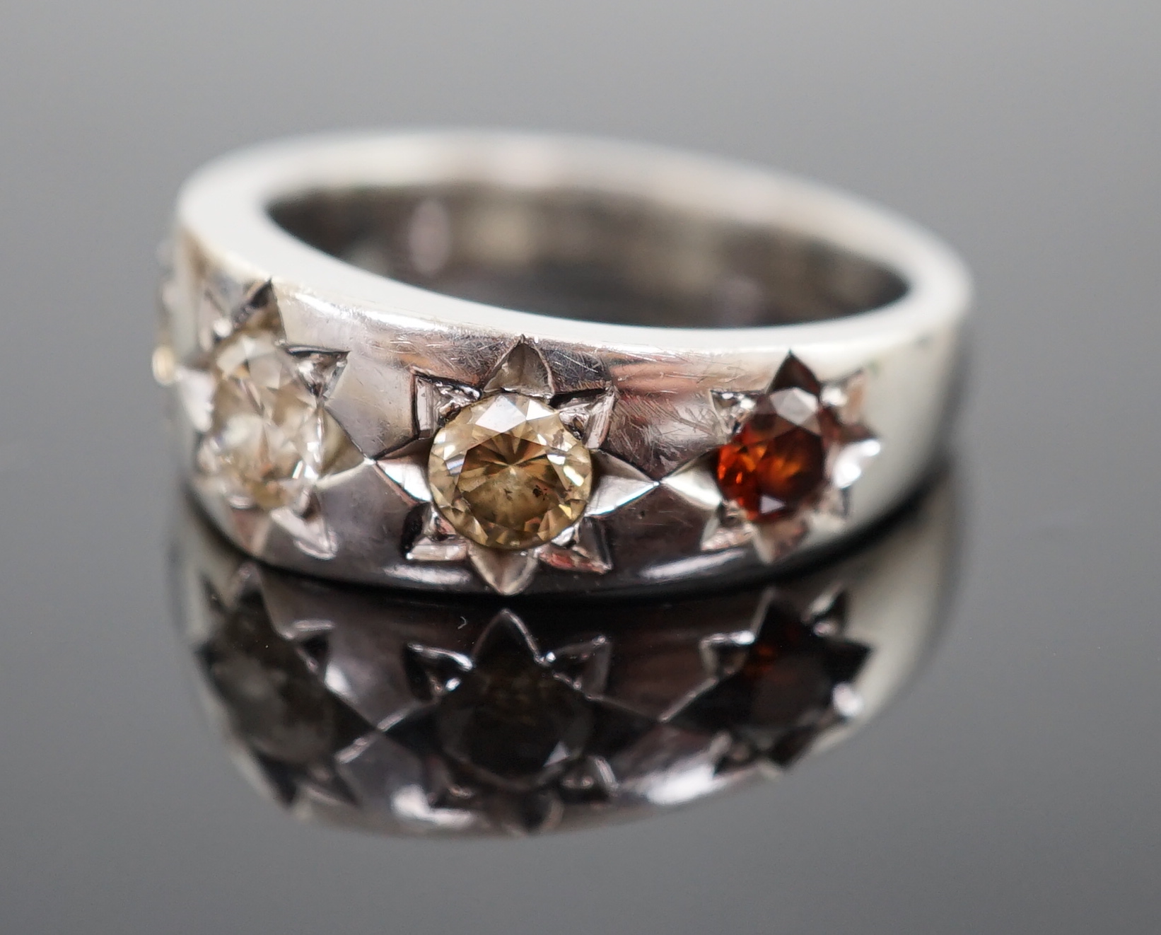 A modern bespoke 18ct white gold and graduated gypsy set five stone coloured diamond set ring